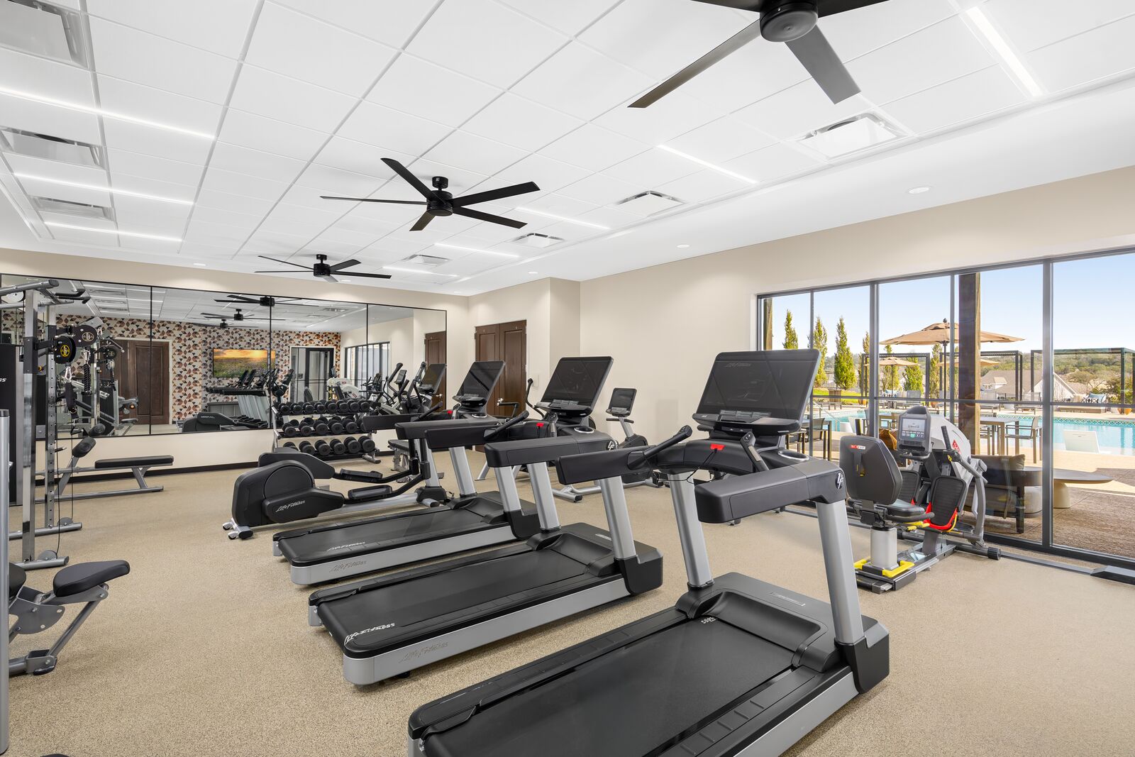Fitness center with treadmills and pool views at The Hacienda, Regency at Esperanza